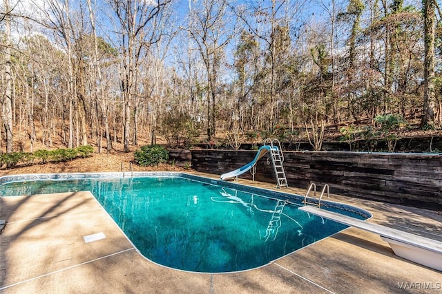 view of pool with a water slide and a diving board