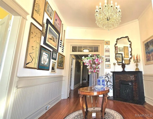 miscellaneous room featuring crown molding, a brick fireplace, dark wood-type flooring, and a chandelier