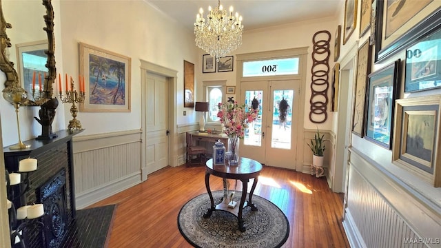 foyer with hardwood / wood-style floors, ornamental molding, french doors, and a chandelier