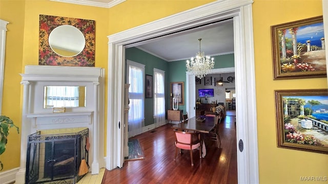 dining room featuring a tiled fireplace, crown molding, hardwood / wood-style floors, and a notable chandelier