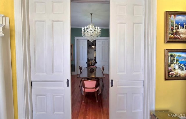 hall featuring hardwood / wood-style flooring, ornamental molding, and a notable chandelier