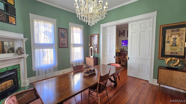 dining area featuring crown molding, dark wood-type flooring, a notable chandelier, and a fireplace