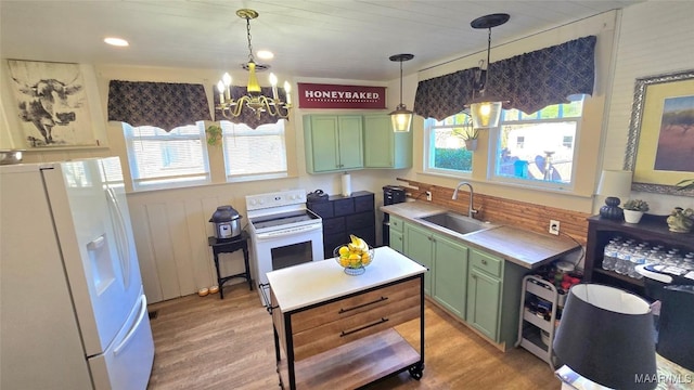 kitchen with hanging light fixtures, sink, green cabinets, and white appliances