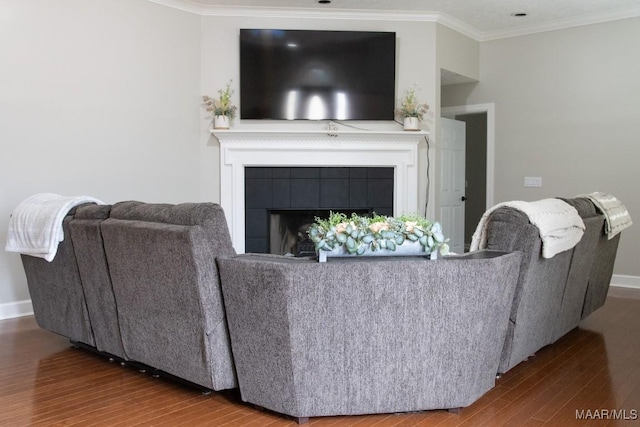 living room with ornamental molding, a tiled fireplace, and hardwood / wood-style floors