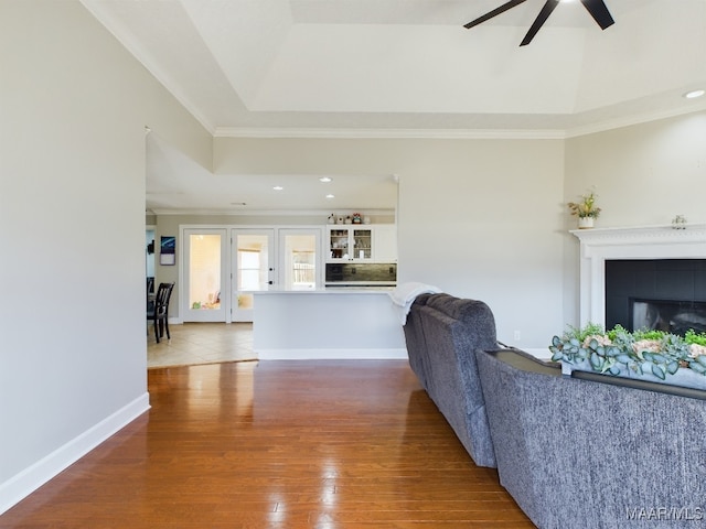 living room with ornamental molding, a fireplace, baseboards, and wood finished floors