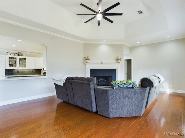 living area with dark wood-style floors, visible vents, a fireplace, and a tray ceiling