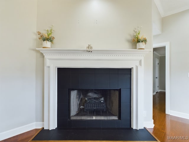 room details featuring ornamental molding, a fireplace, baseboards, and wood finished floors