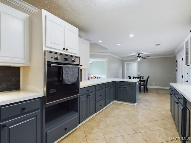 kitchen with stainless steel oven, light tile patterned floors, white cabinetry, and light countertops