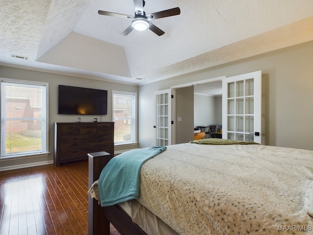 bedroom with french doors, dark wood finished floors, a raised ceiling, visible vents, and a textured ceiling