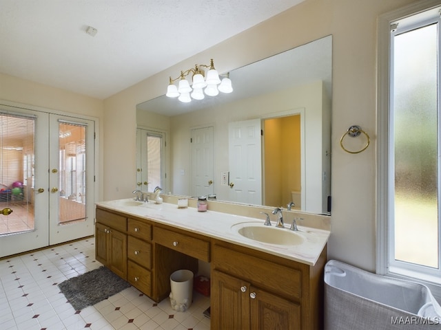 full bath featuring double vanity, toilet, a sink, and french doors