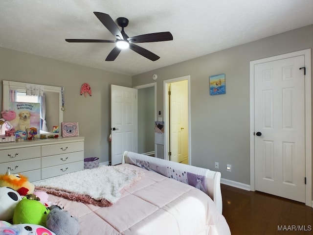 bedroom featuring dark wood-type flooring, a ceiling fan, and baseboards