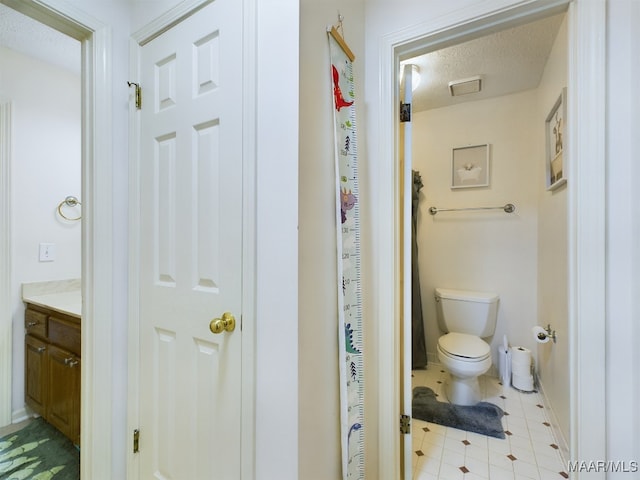 full bathroom featuring a textured ceiling, vanity, and toilet