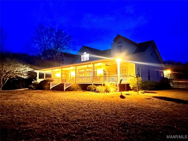 back house at night with ceiling fan and covered porch