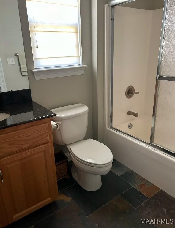 bathroom with combined bath / shower with glass door, vanity, and toilet