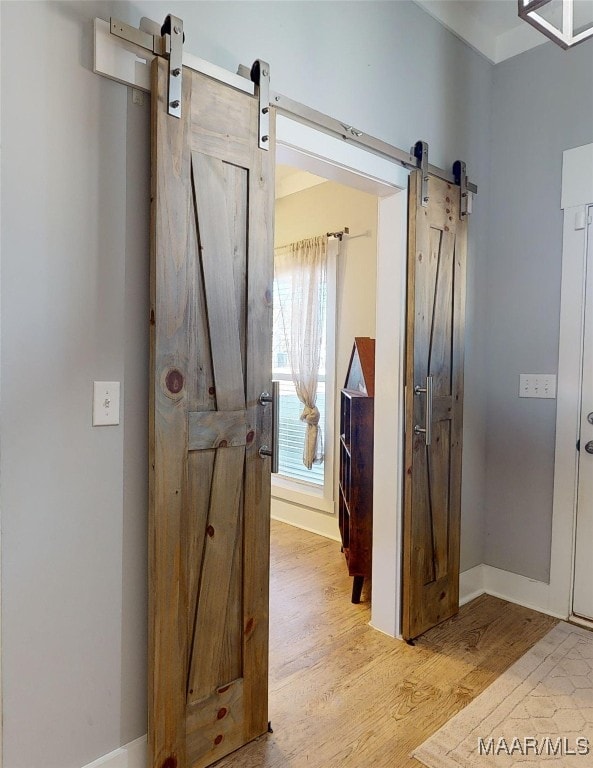 hall featuring a barn door and light hardwood / wood-style flooring