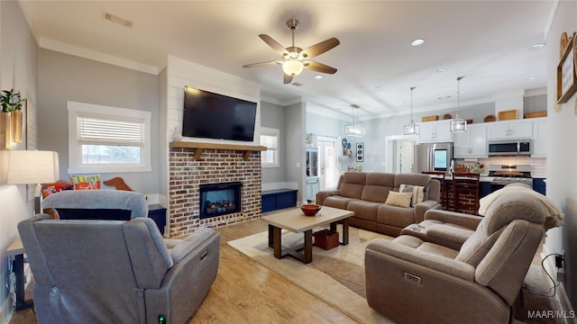 living room featuring ornamental molding, plenty of natural light, light hardwood / wood-style floors, and a brick fireplace