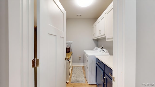 washroom featuring light hardwood / wood-style flooring, washing machine and dryer, and cabinets