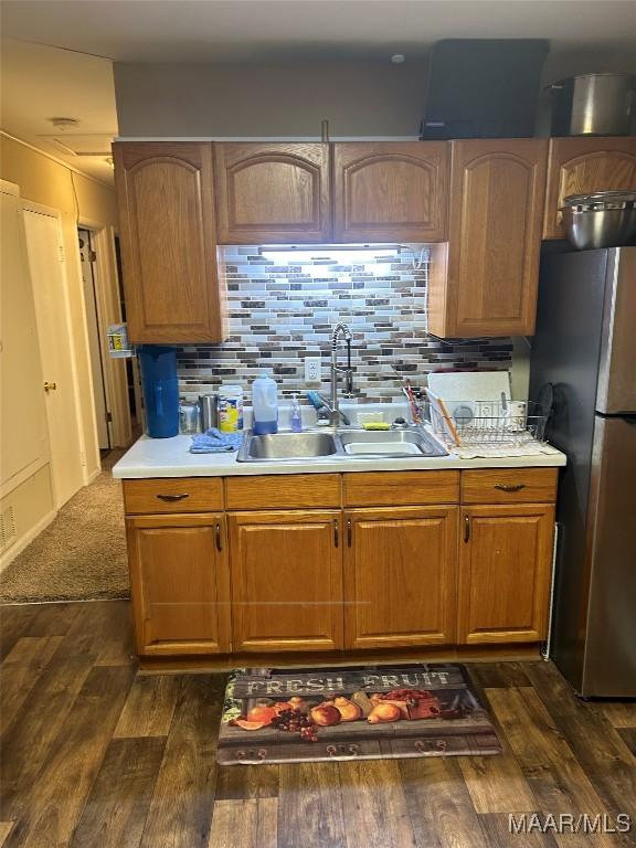 kitchen with dark hardwood / wood-style floors, sink, stainless steel refrigerator, and decorative backsplash