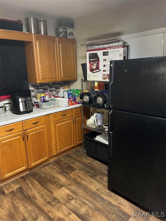 kitchen featuring decorative backsplash, dark hardwood / wood-style floors, and black fridge