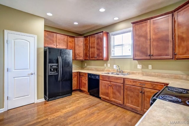 kitchen with sink, light hardwood / wood-style floors, and black appliances