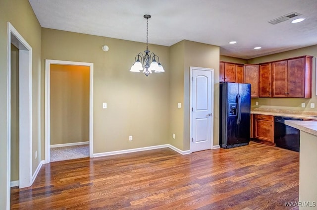 kitchen with dark hardwood / wood-style flooring, hanging light fixtures, black appliances, and an inviting chandelier