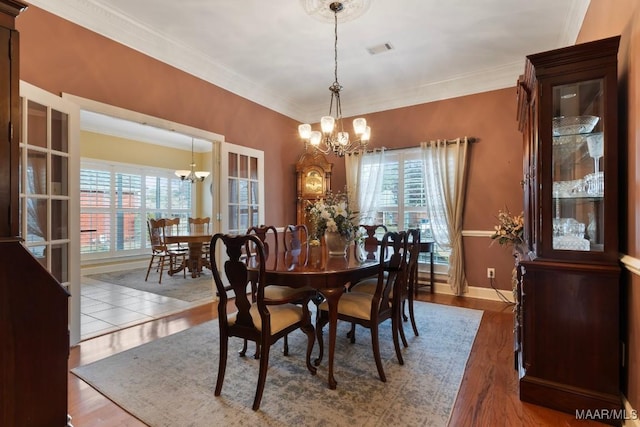 dining area featuring hardwood / wood-style floors, crown molding, a wealth of natural light, and a chandelier