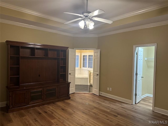 unfurnished bedroom featuring ensuite bathroom, hardwood / wood-style floors, ornamental molding, a walk in closet, and ceiling fan