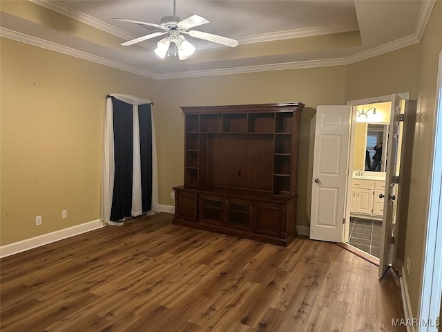 interior space with connected bathroom, hardwood / wood-style flooring, ceiling fan, a raised ceiling, and crown molding