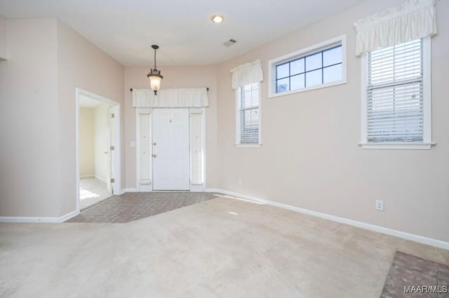 carpeted foyer entrance with a wealth of natural light