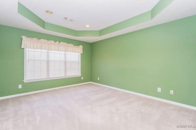 carpeted empty room featuring a tray ceiling