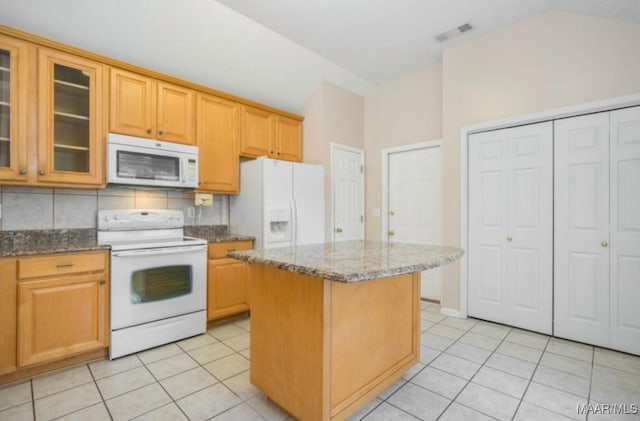 kitchen with tasteful backsplash, light stone counters, light tile patterned floors, a kitchen island, and white appliances