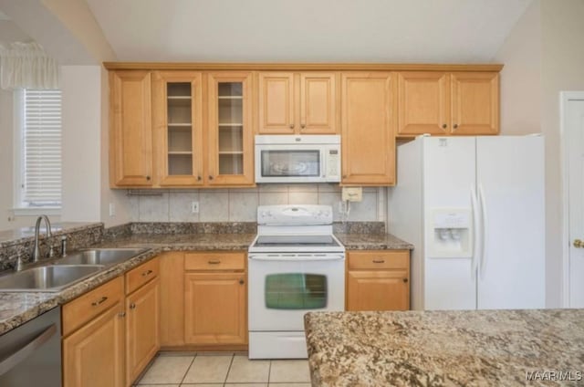 kitchen featuring light tile patterned flooring, sink, white appliances, and dark stone counters