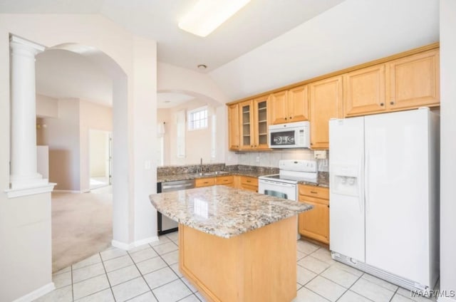 kitchen with light stone counters, light carpet, a kitchen island, white appliances, and decorative columns