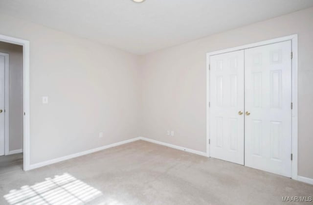 unfurnished bedroom with light colored carpet and a closet