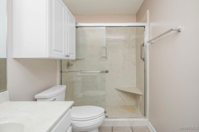 bathroom with vanity, a shower with door, tile patterned floors, and toilet