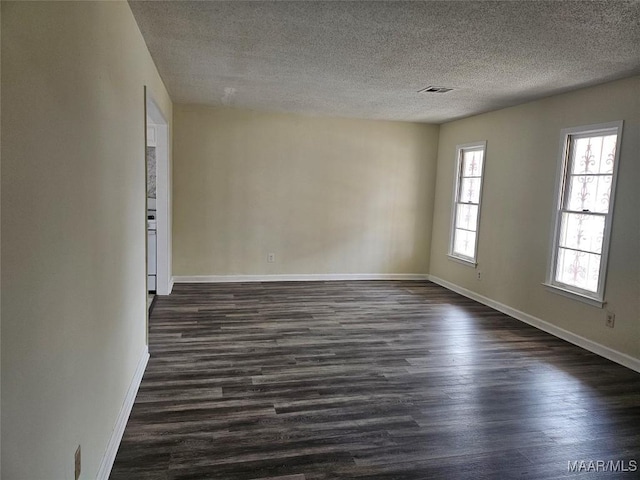 empty room with dark wood-type flooring and a textured ceiling