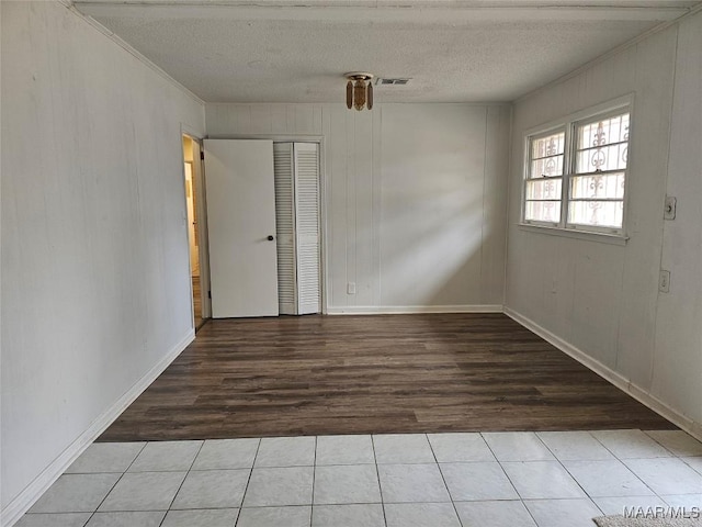 empty room featuring ornamental molding, a textured ceiling, and light tile patterned flooring