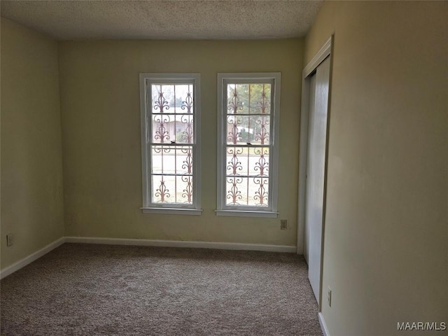 carpeted empty room featuring a textured ceiling