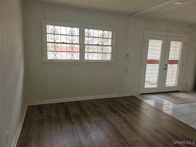 entryway featuring dark hardwood / wood-style floors, wood walls, a textured ceiling, and french doors