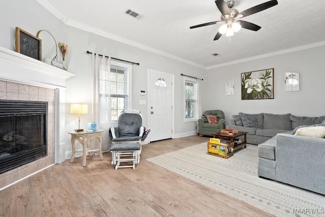 living room featuring a fireplace, a wealth of natural light, light hardwood / wood-style flooring, and ornamental molding