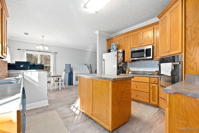 kitchen with a kitchen island, appliances with stainless steel finishes, decorative light fixtures, tasteful backsplash, and ornamental molding