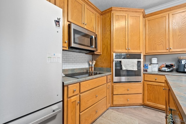 kitchen featuring stainless steel appliances, crown molding, backsplash, and light hardwood / wood-style flooring