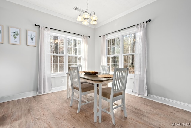 dining room with an inviting chandelier, crown molding, and light hardwood / wood-style floors