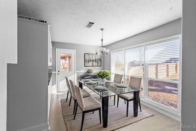 dining space with a textured ceiling and a chandelier