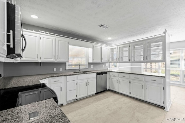 kitchen featuring appliances with stainless steel finishes, sink, dark stone countertops, and white cabinets