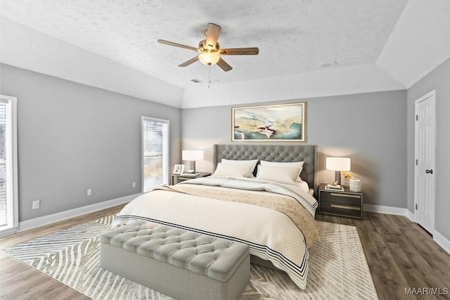 bedroom featuring a raised ceiling, ceiling fan, dark hardwood / wood-style floors, and a textured ceiling