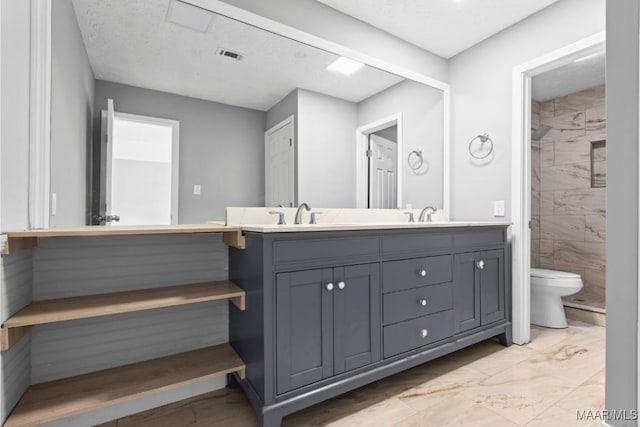 bathroom with vanity, a tile shower, a textured ceiling, and toilet