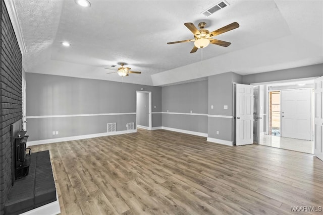 unfurnished living room with hardwood / wood-style flooring, ceiling fan, a raised ceiling, and a textured ceiling