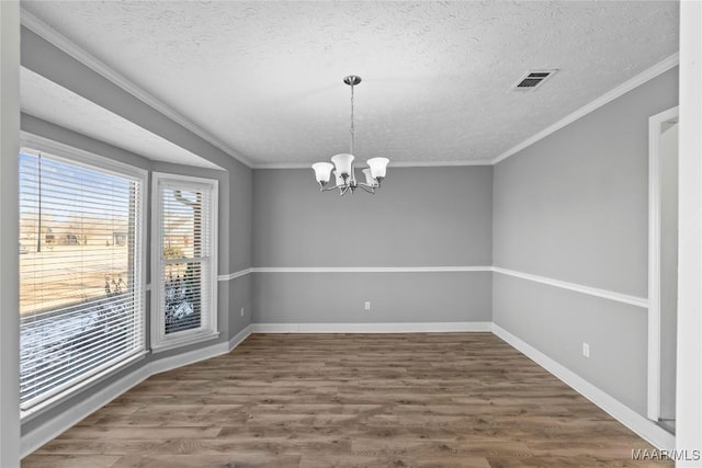 spare room featuring crown molding, a textured ceiling, dark hardwood / wood-style floors, and a chandelier