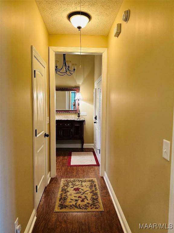 corridor with dark wood-type flooring and a textured ceiling